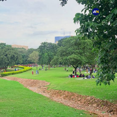 People relaxing and picnicking across the expansive green lawns and shaded tree areas at Millennium Park in Maitama, Abuja.